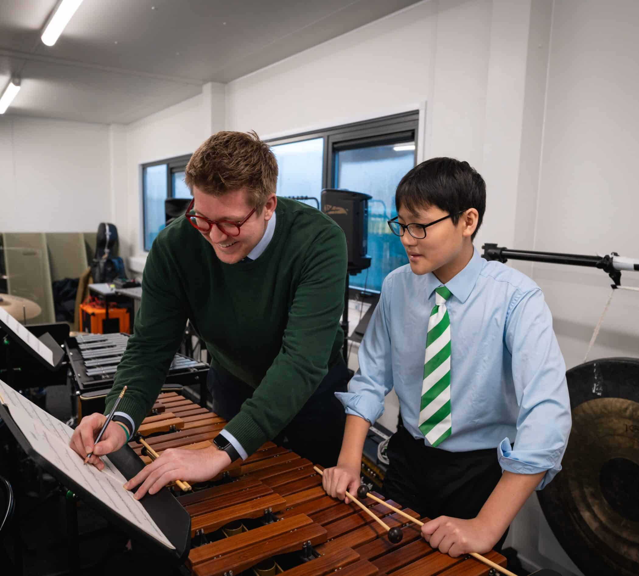 Boy has bagpipes lesson with male teacher in a small room with piano