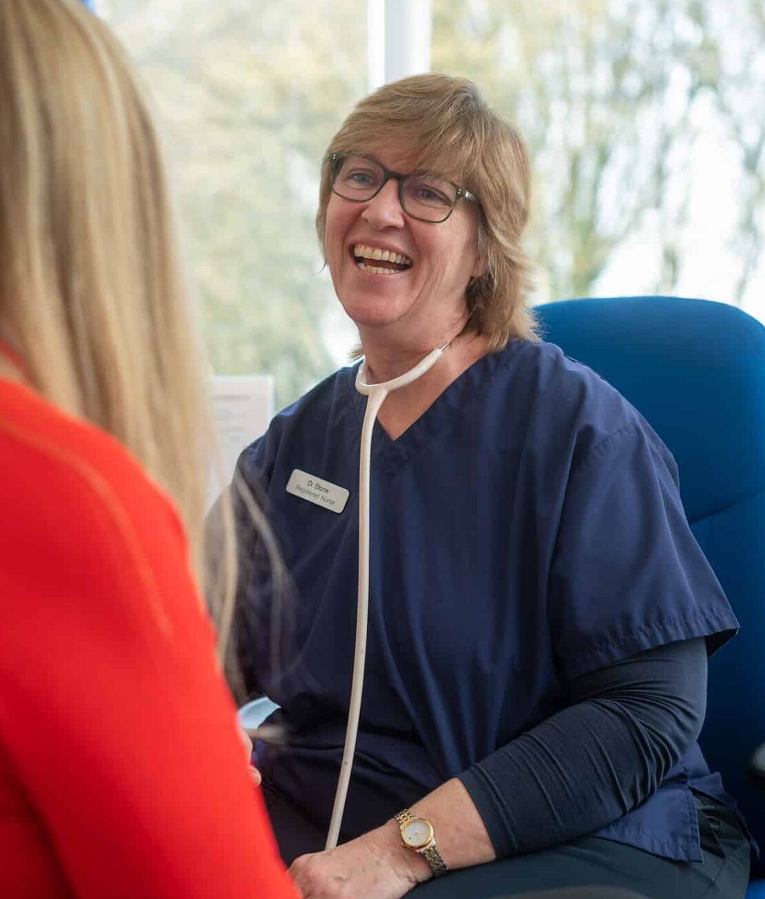 Nurse dressed in blue attending to a lady in a medical centre