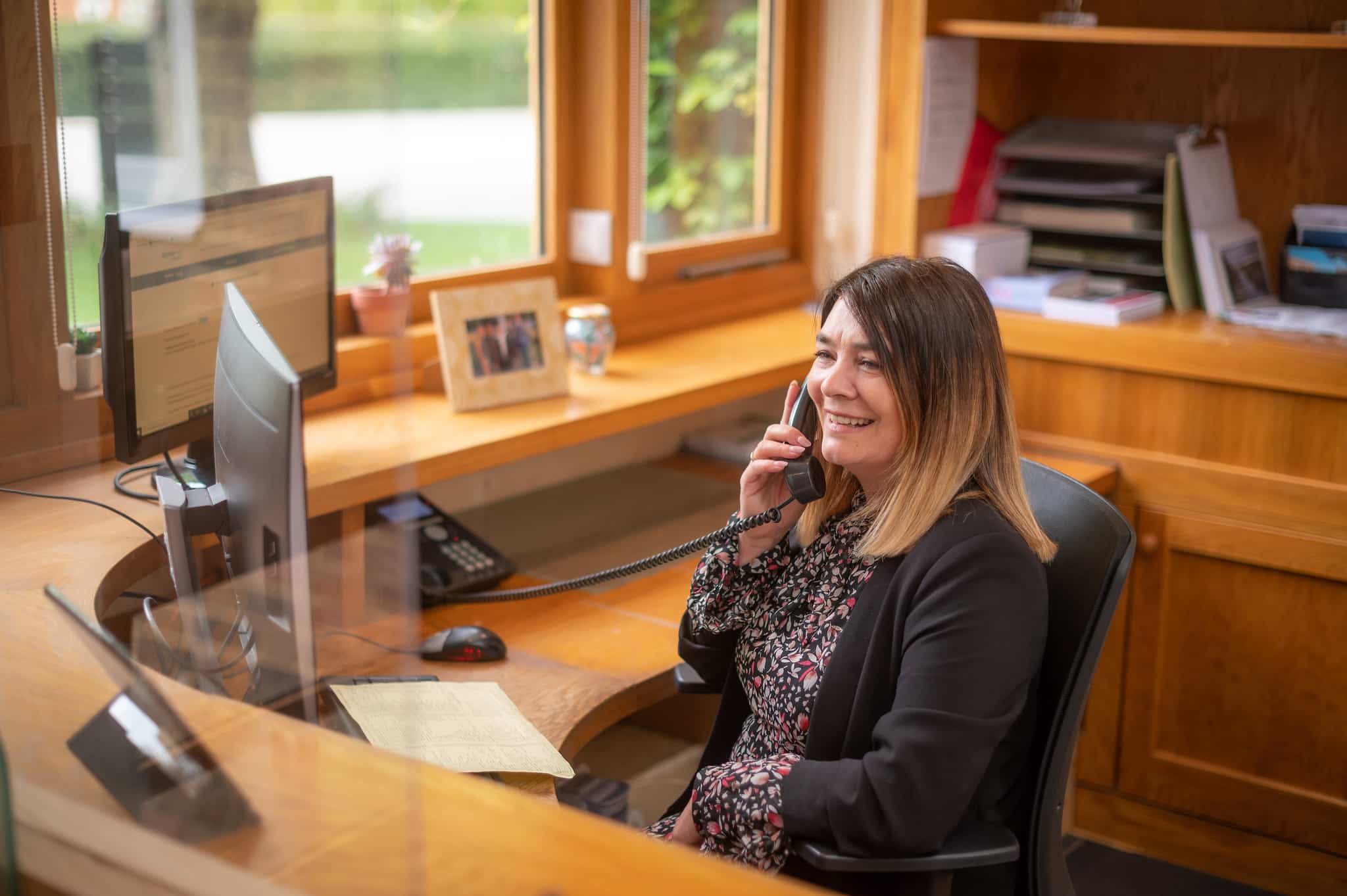 Receptionist on the phone whilst smiling in a pleasant office area