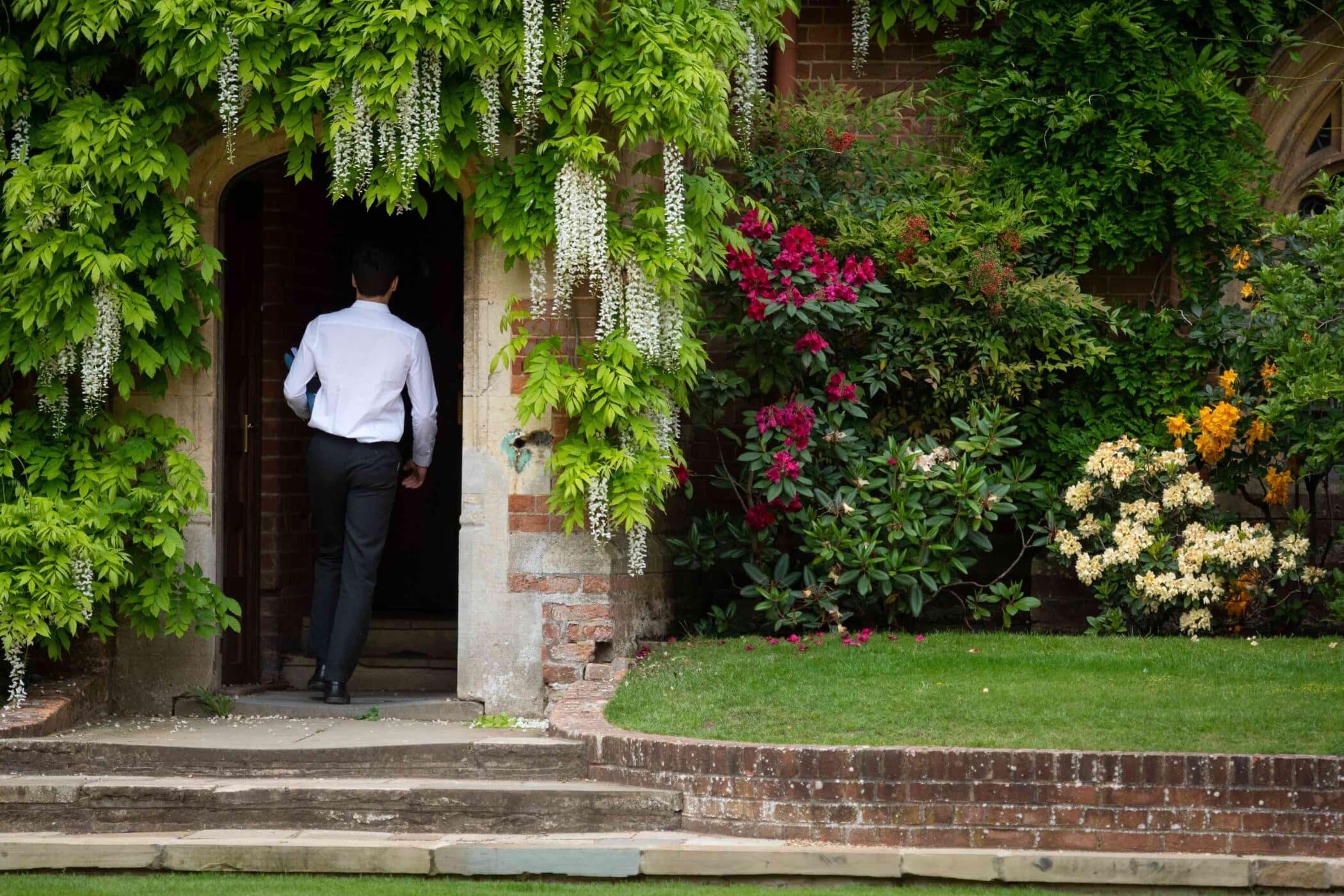 Boy walking through flowered doorway at Radley College