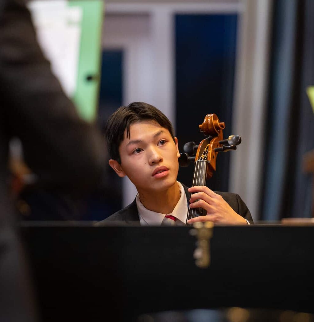 boy playing a cello as part of an orchestra
