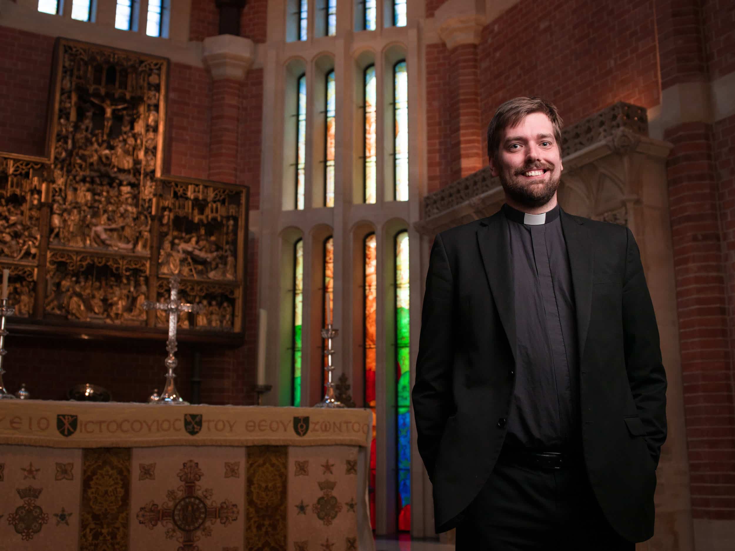 Bob Evans Chaplain of Radley College stood in the Chapel with stained glass windows