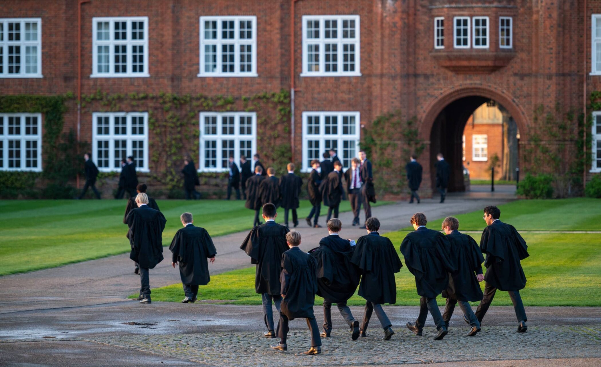 Boys in gowns walking through the grounds of Radley College in Oxfordshire