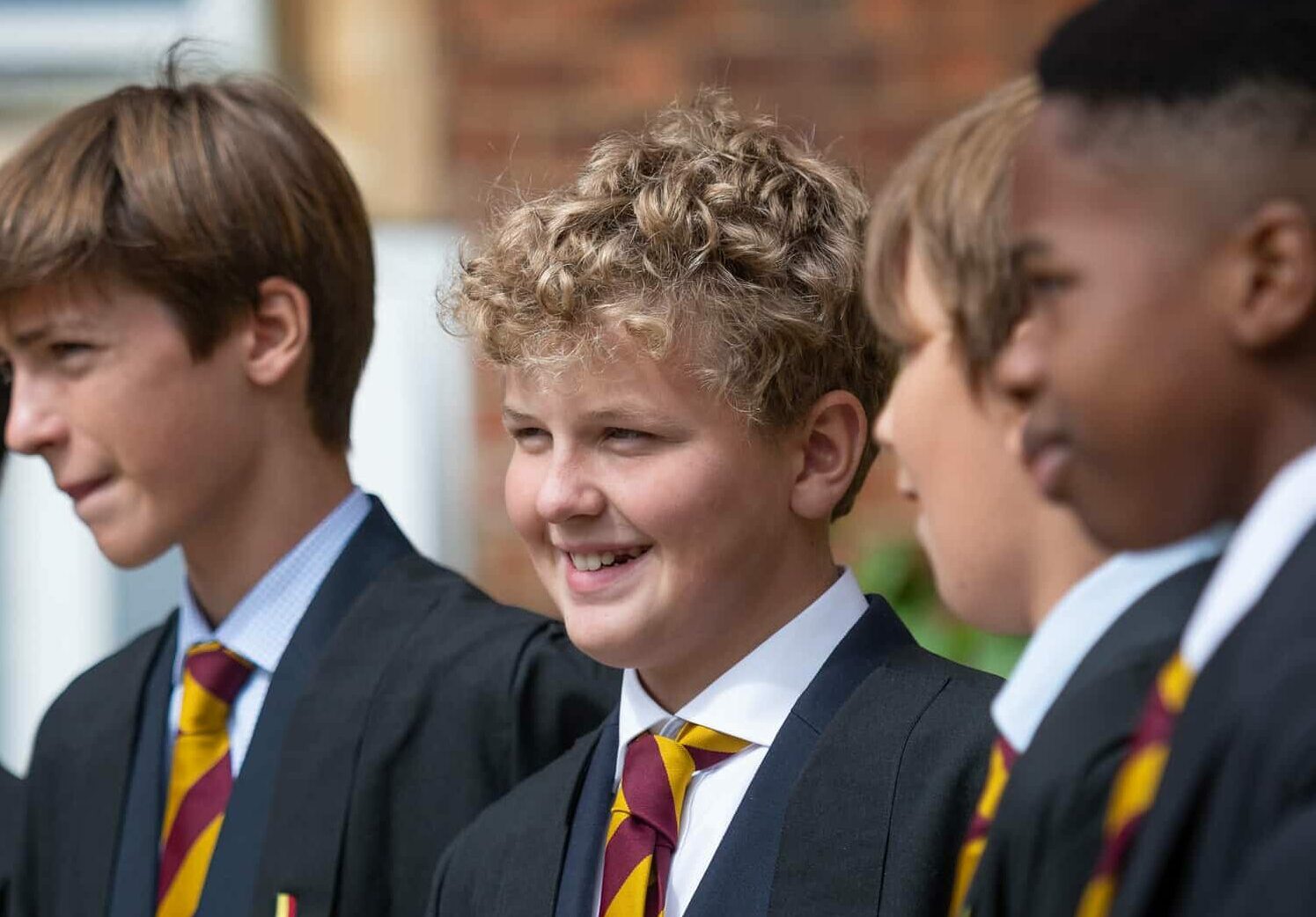 Blonde boy stood amongst group of boys in school uniform at Radley College