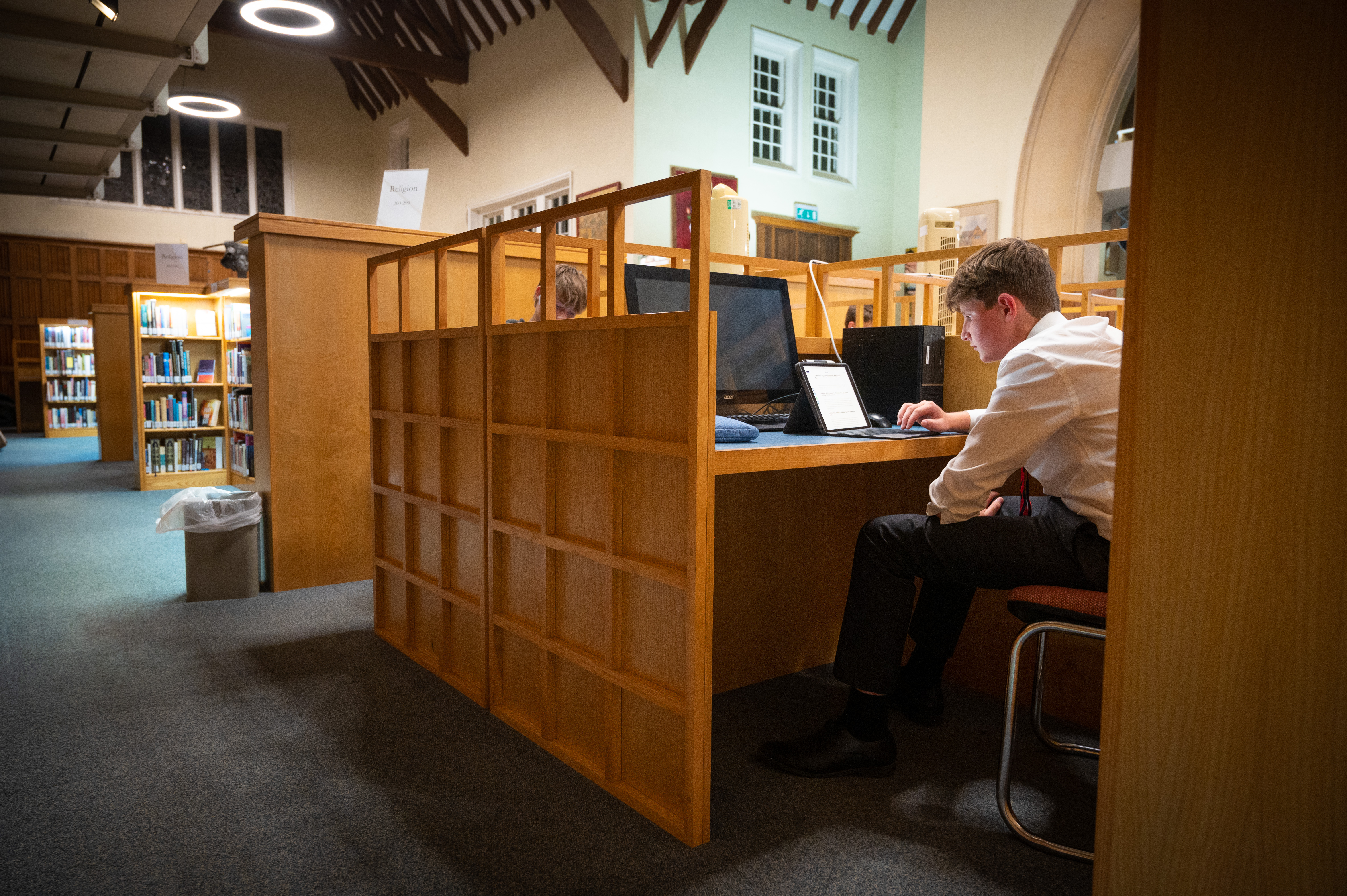 Boy working in the library at Radley College, from behind