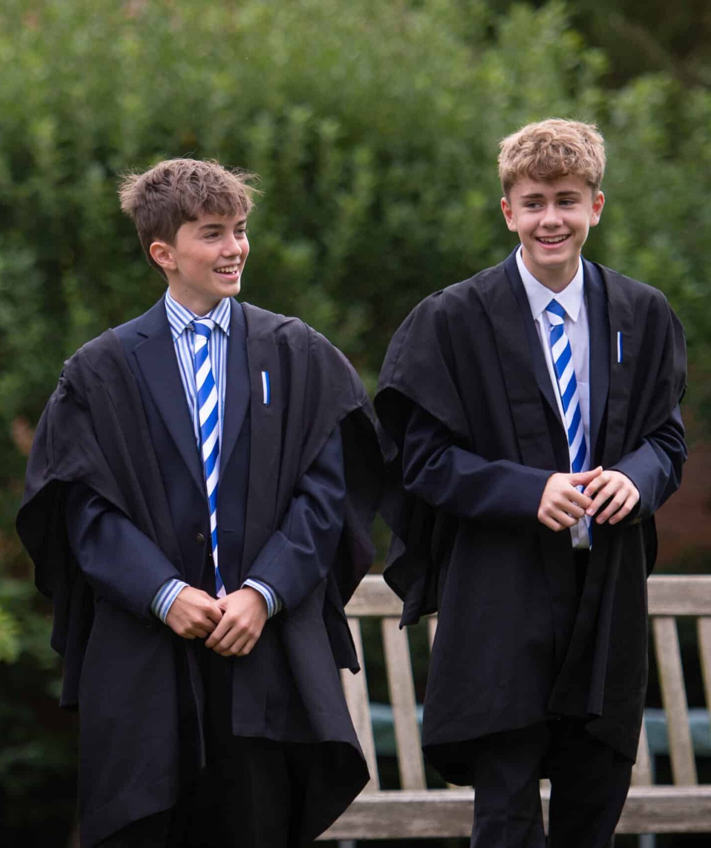 Three boys in ties and gowns in a garden at Radley College
