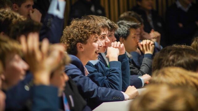 Boy sat in a large crowd laughing and smiling